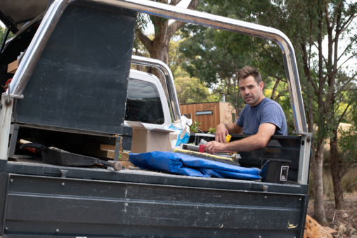 Tradie grabbing tools from ute on a constructions site