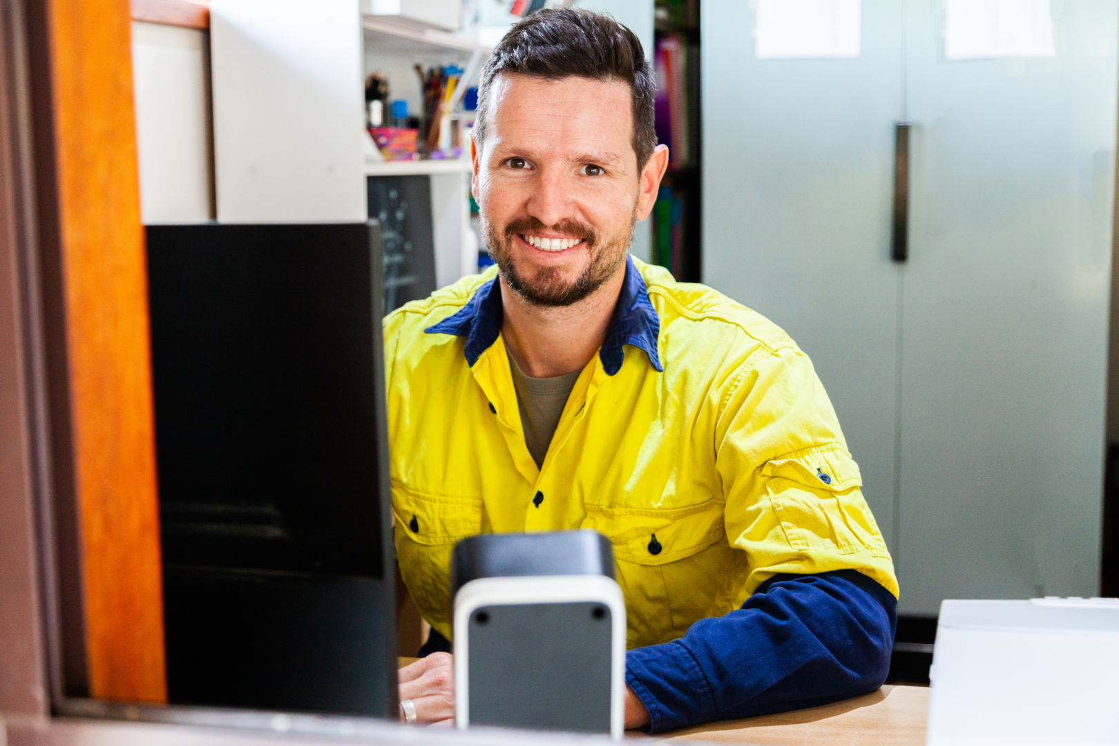 Australian tradie smiling while doing bookwork on computer.