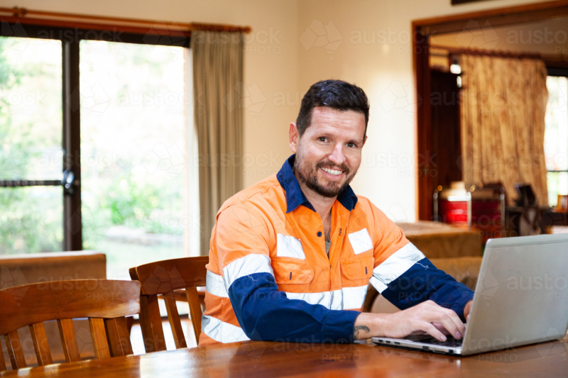 Australian tradie reviewing his invoices and receipts on computer after work